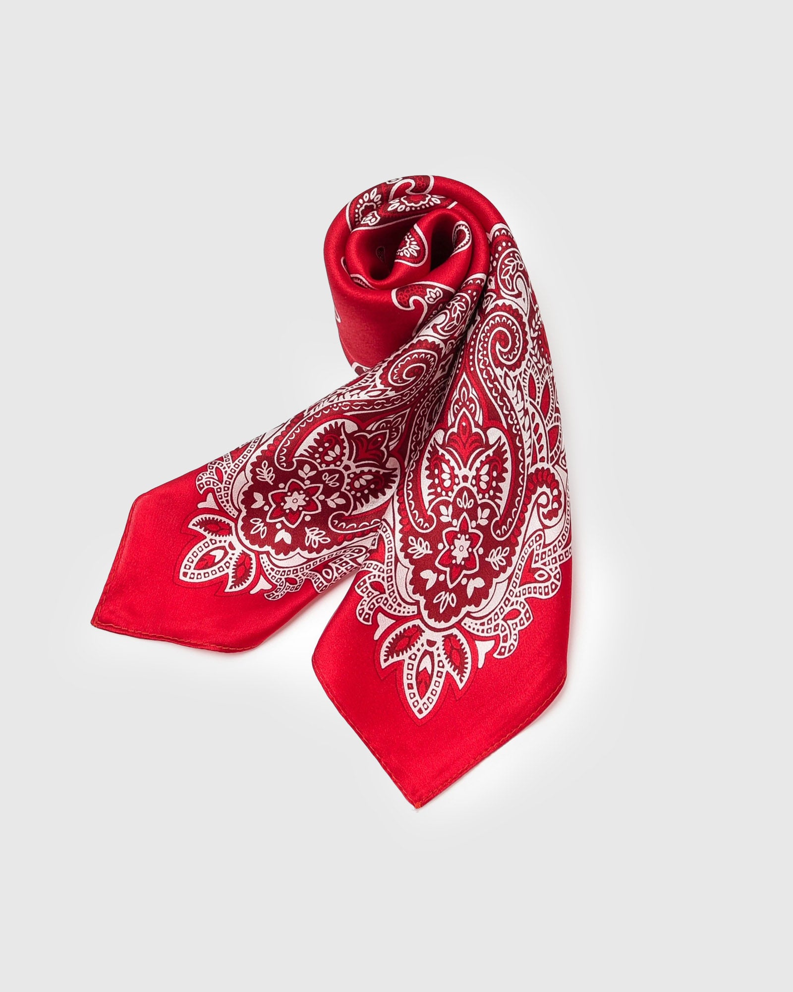 Crimson silk bandana scarf in a soft fold showing the ivory paisley pattern against the red ground
```