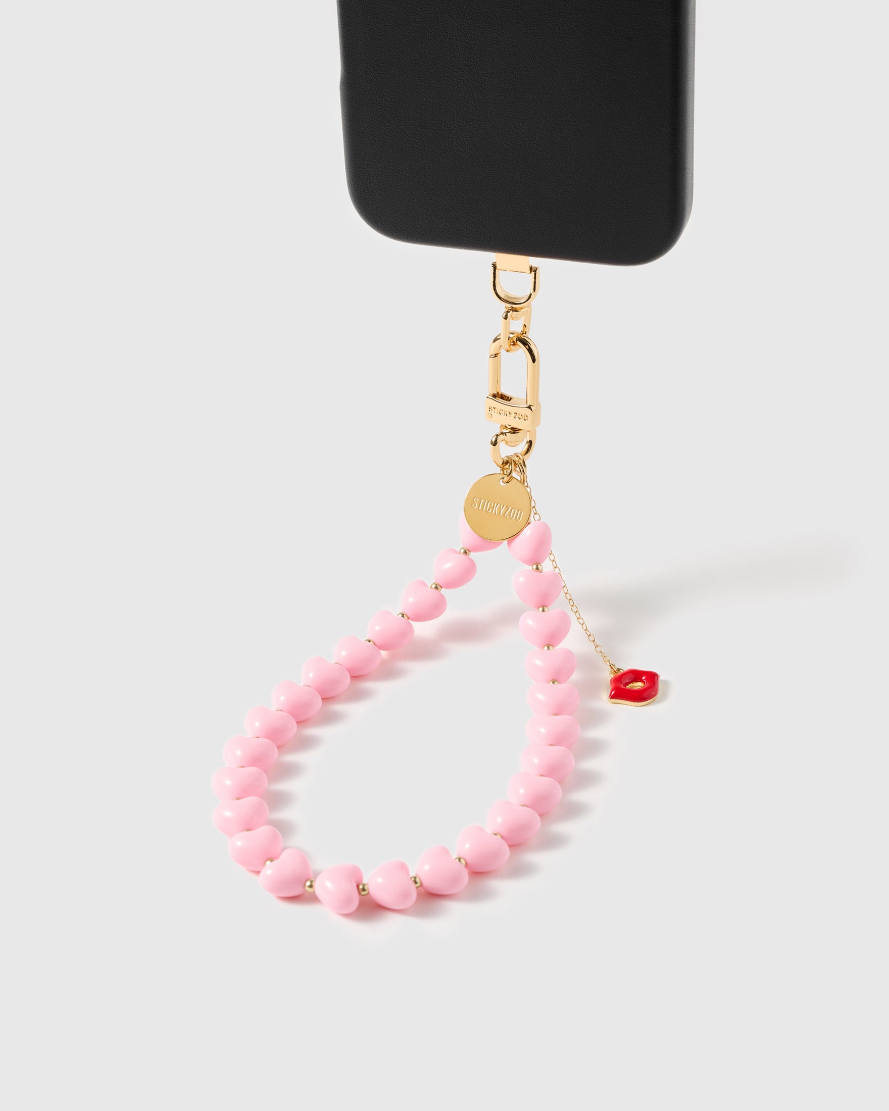 Close-up of glossy pink heart beads and gold spacers strung by hand, kiss charm catching light