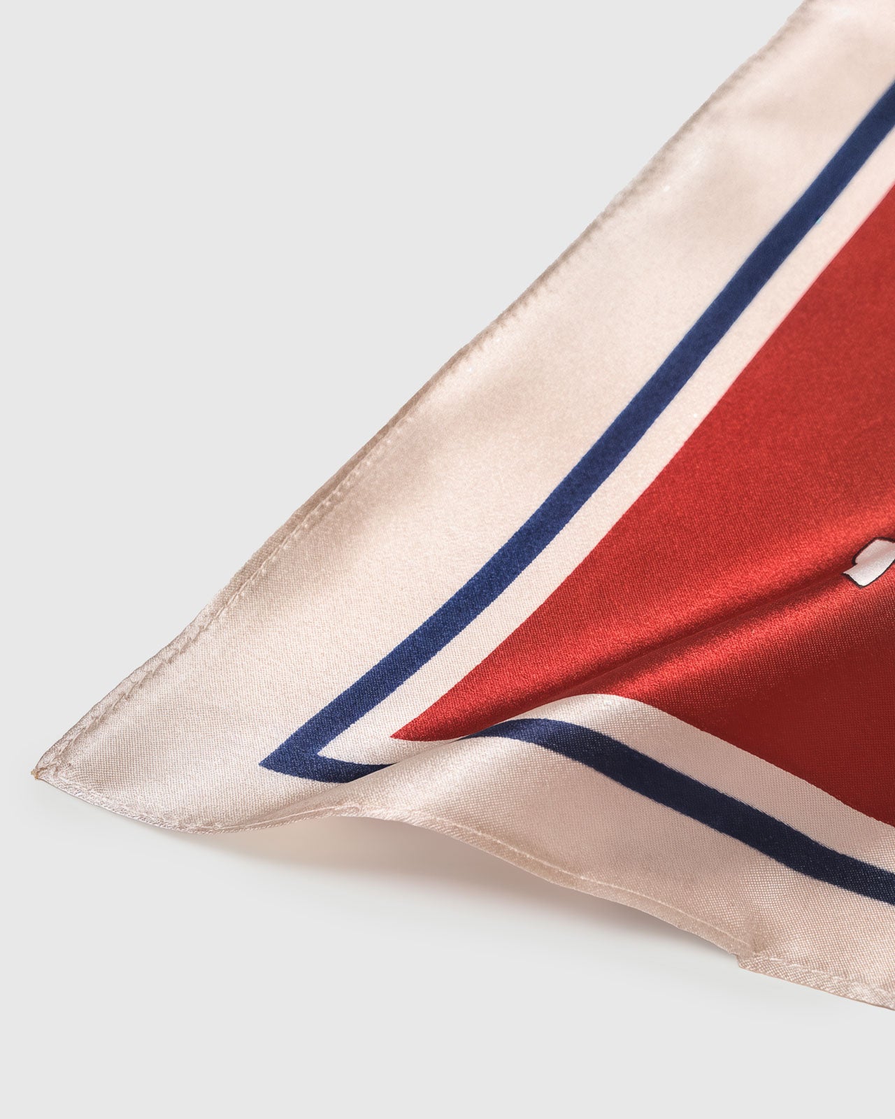 Silk scarf corner folded to reveal the rust border meeting the sky-blue field and the soft pure-silk drape
```