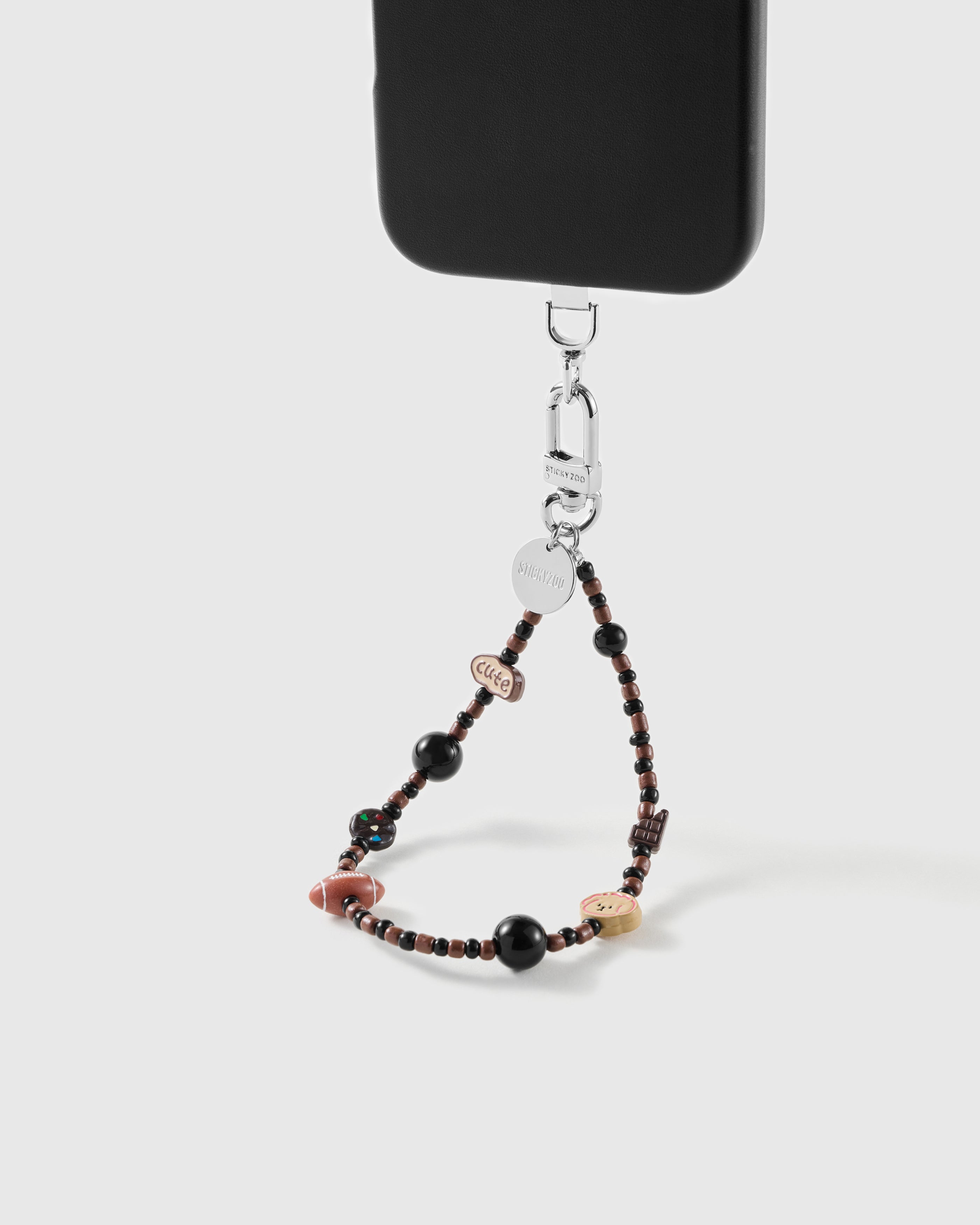 Puppy picnic charm wrist strap clipped to a black phone case for hands-free carry