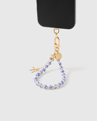 Porcelain bloom charm phone strap hanging from black phone case showing wrist carry