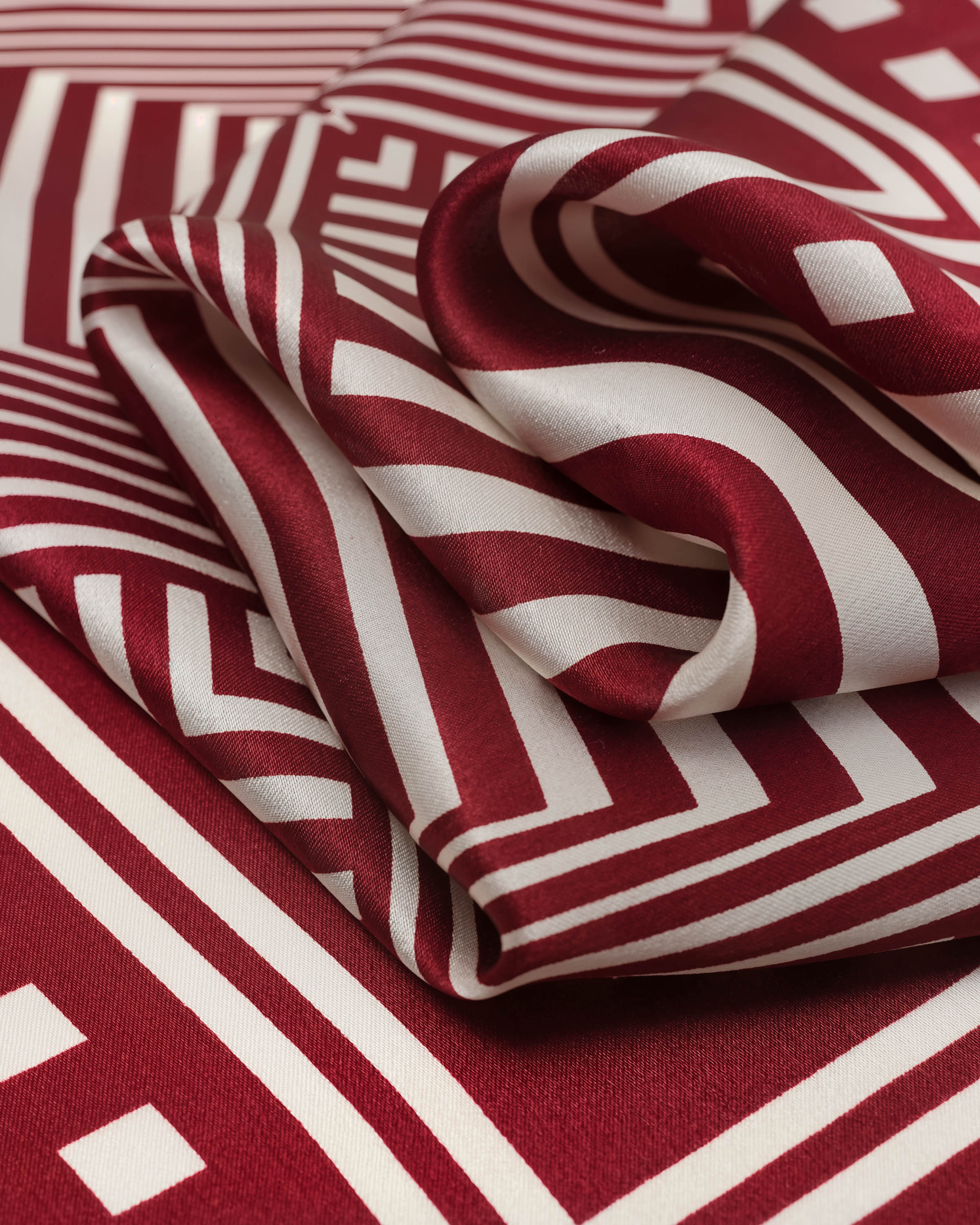 STICKYZOO crimson op-art silk scarf folded to show the optical depth of the concentric square print
```