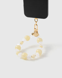 Butter crystal cluster phone strap hanging from black phone case showing wrist carry functionality