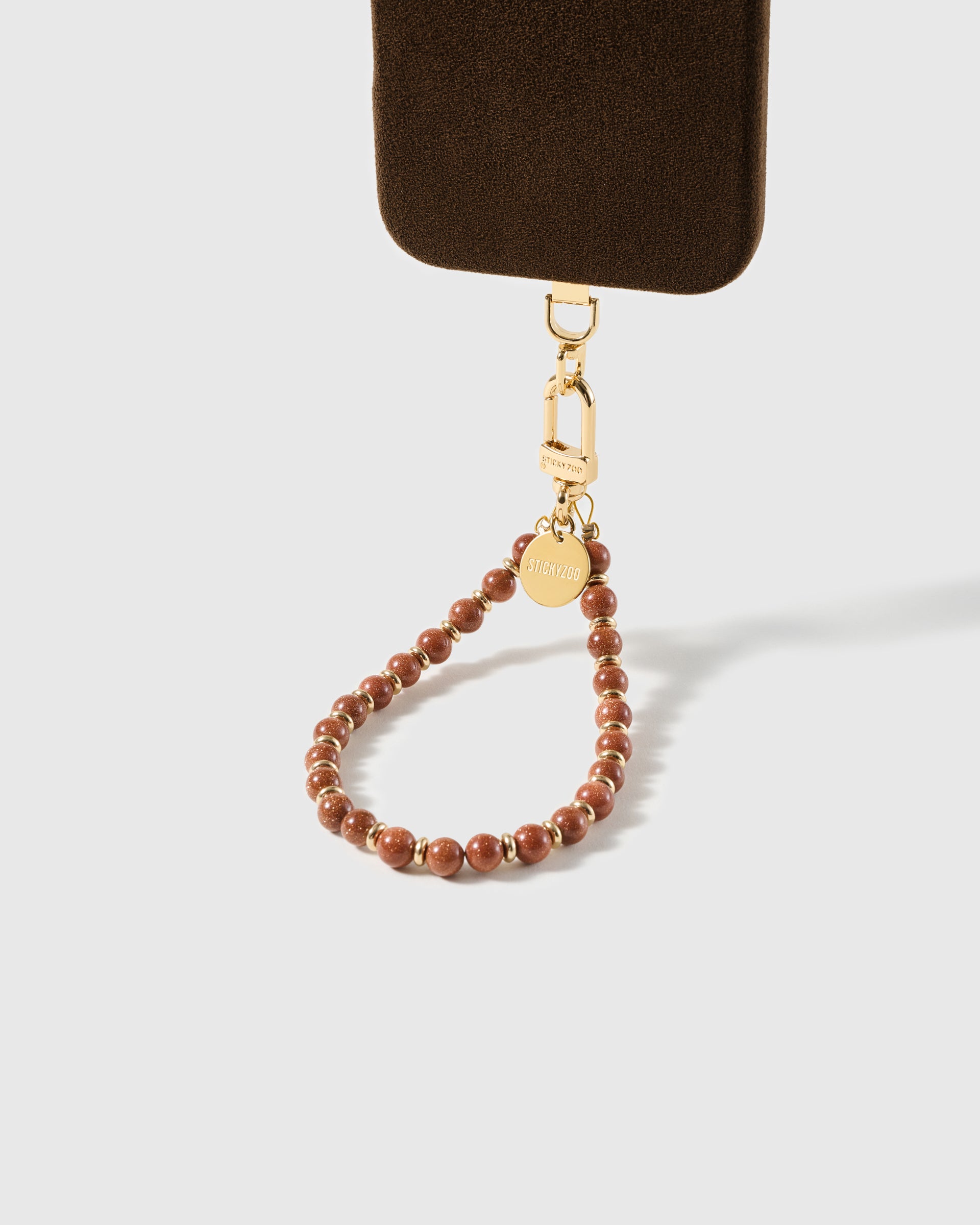 Copper goldstone beaded wrist strap clasped to a phone case with the gold-tone hook visible for universal fit