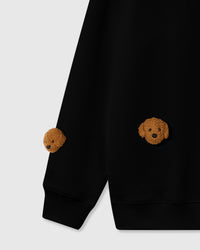 Detail of three plush poodle faces on black cotton showing high-contrast golden fur against dark fabric