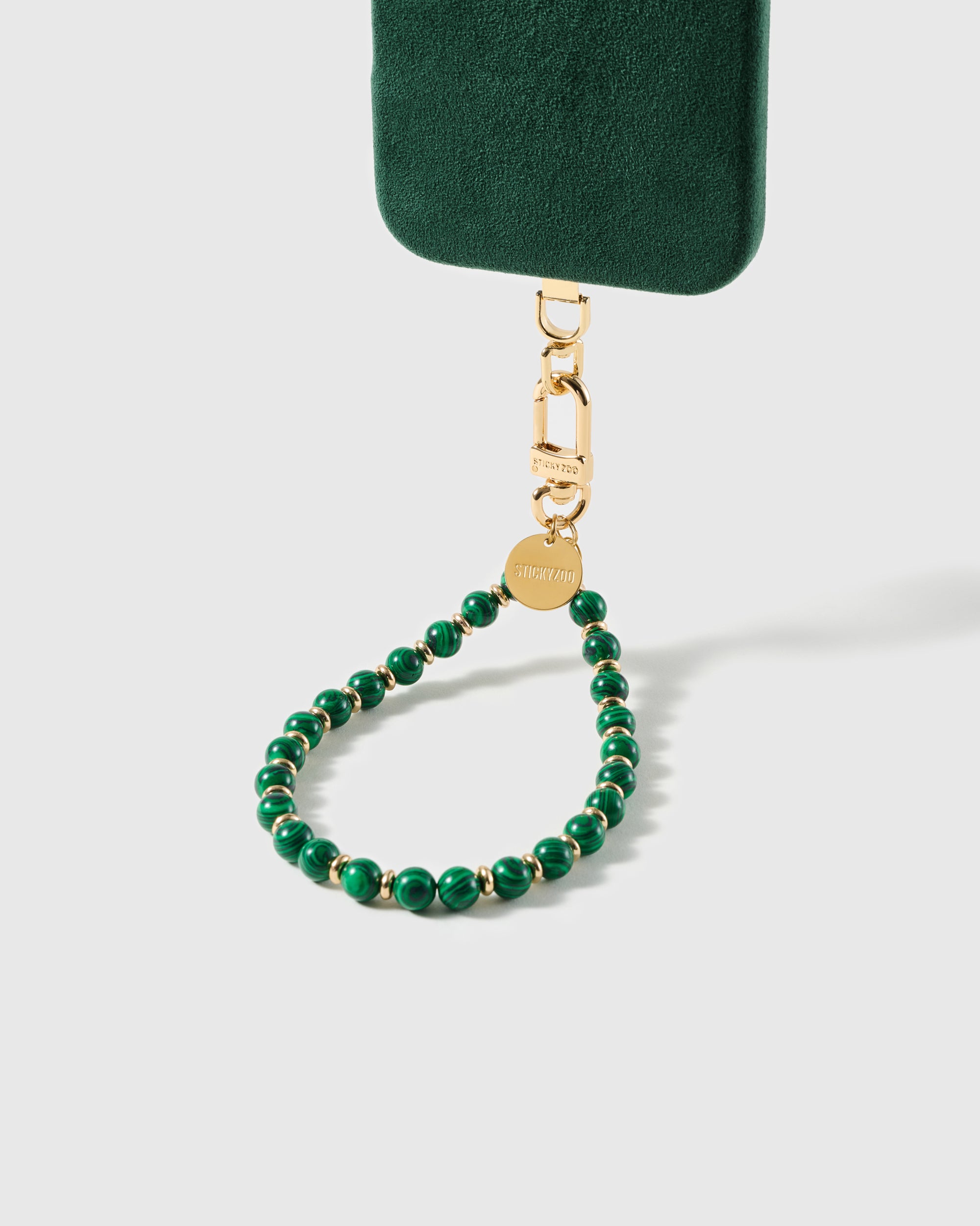 Emerald swirl beaded wrist strap attached to a phone case, gold-plated clasp clipped in for universal fit