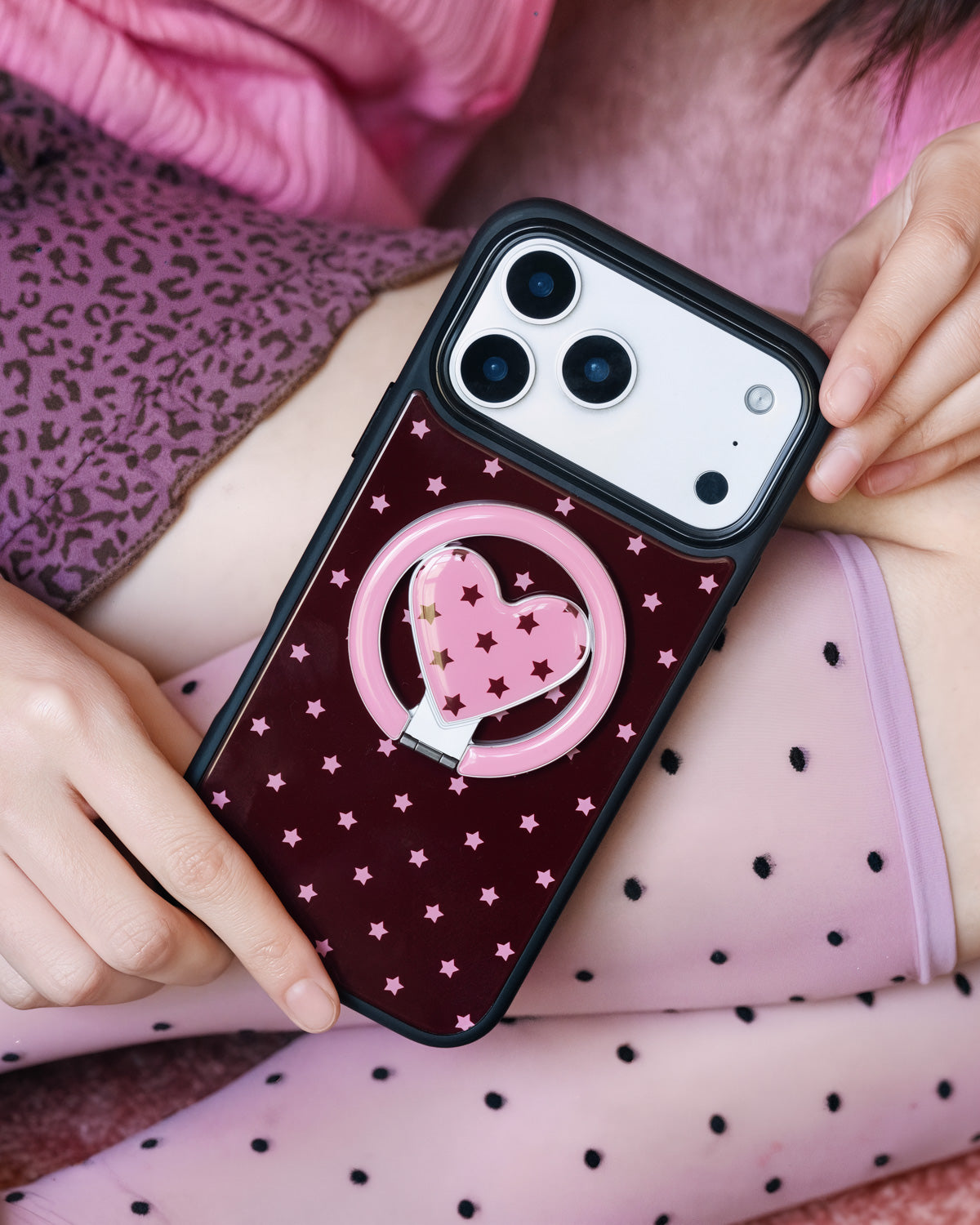 Burgundy starlight heart phone case held close with the heart-in-ring MagSafe kickstand extended