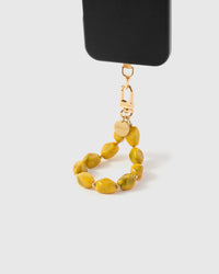 Saffron agate phone strap hanging from black phone case showing golden olive-marbled beads