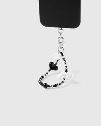 Noir heart cloud phone strap hanging from black phone case showing monochrome wrist carry