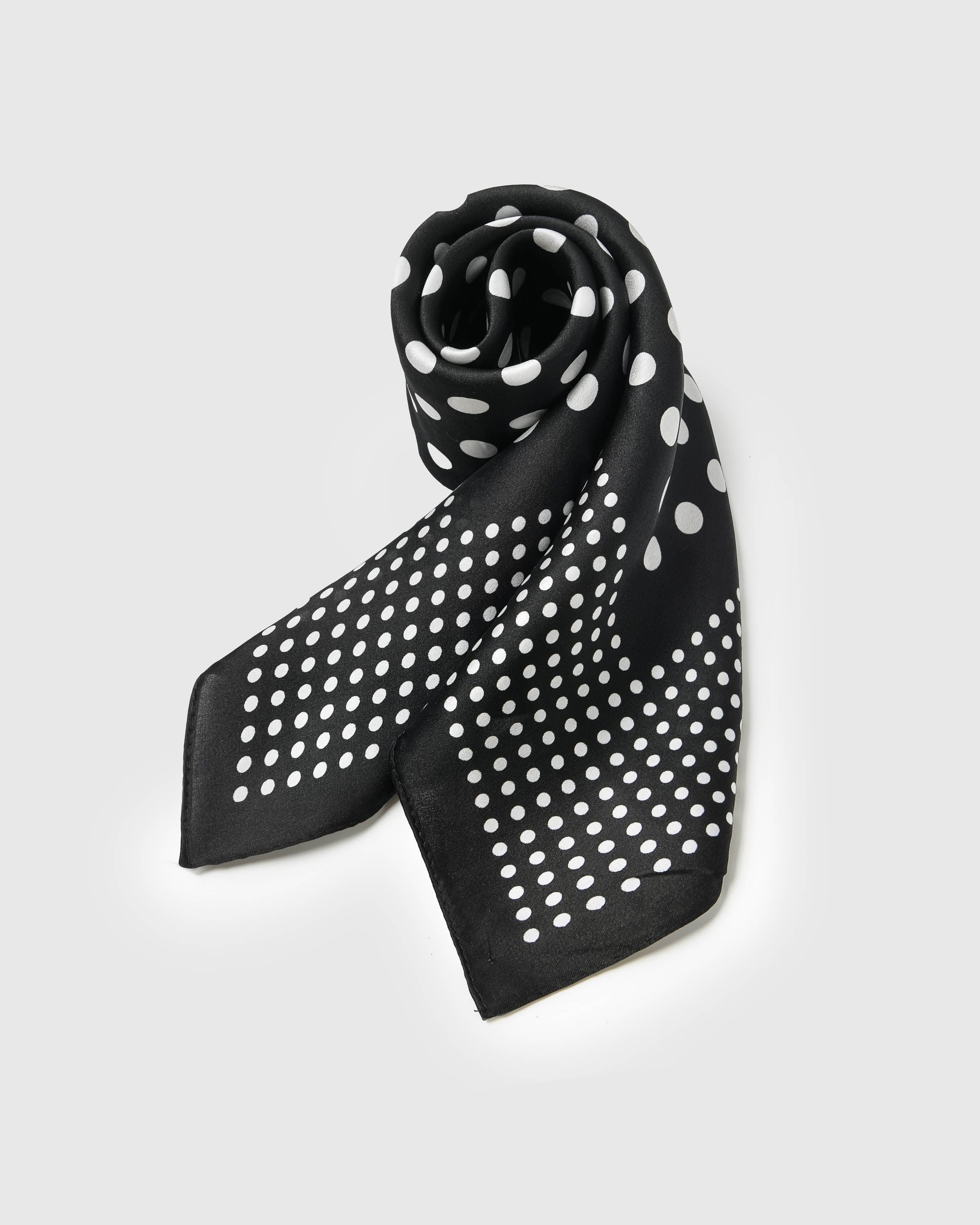 Black silk dot scarf coiled to show the soft drape and bright white print on pure silk
```