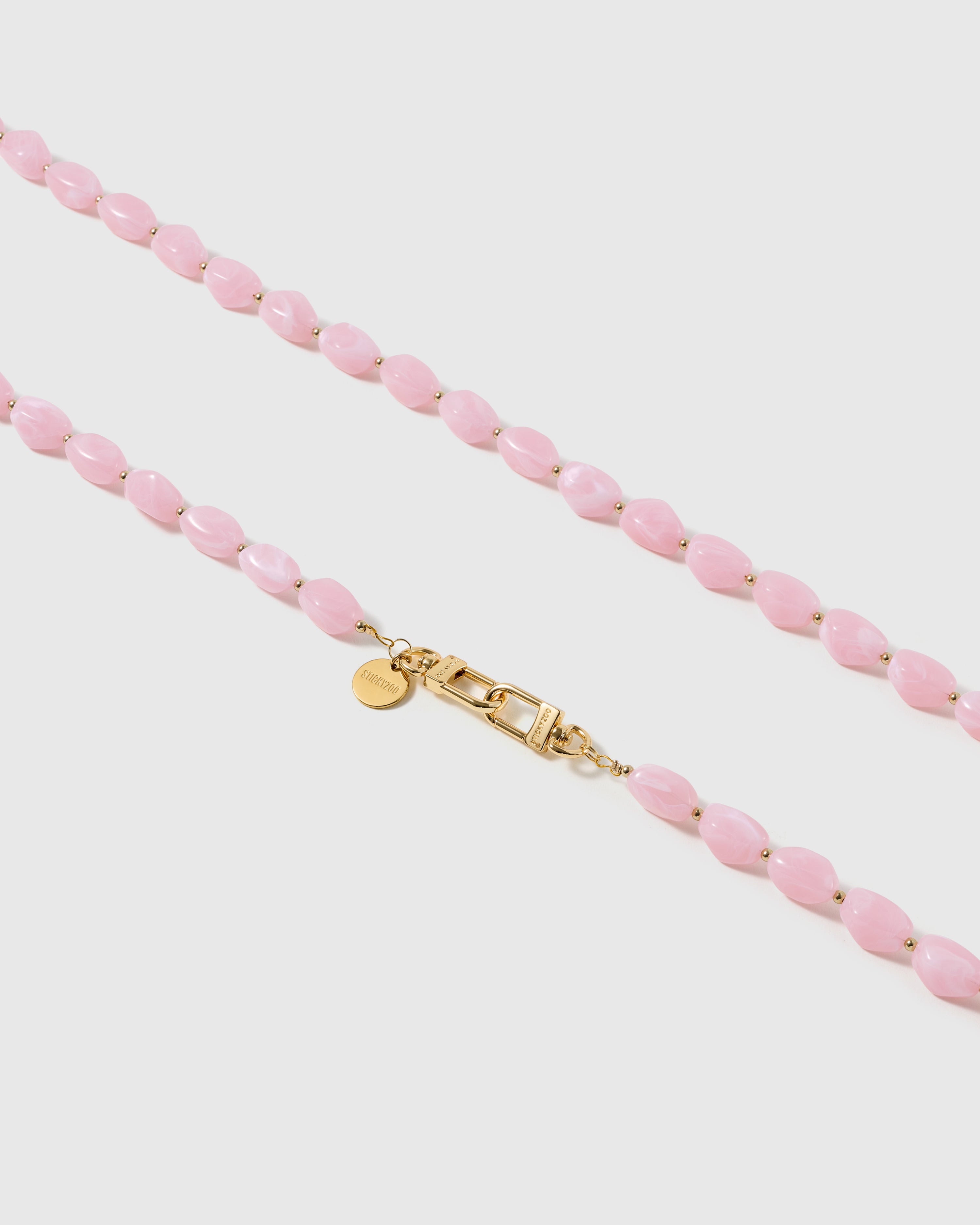 Macro close-up of the polished petal-pink resin beads and gold-plated clasp, each strap assembled by hand