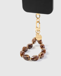 Amber stone strap hanging from black phone case showing natural brown marbling in each bead