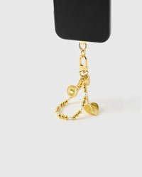 Golden orbit pearl phone strap hanging from black phone case showing wrist carry