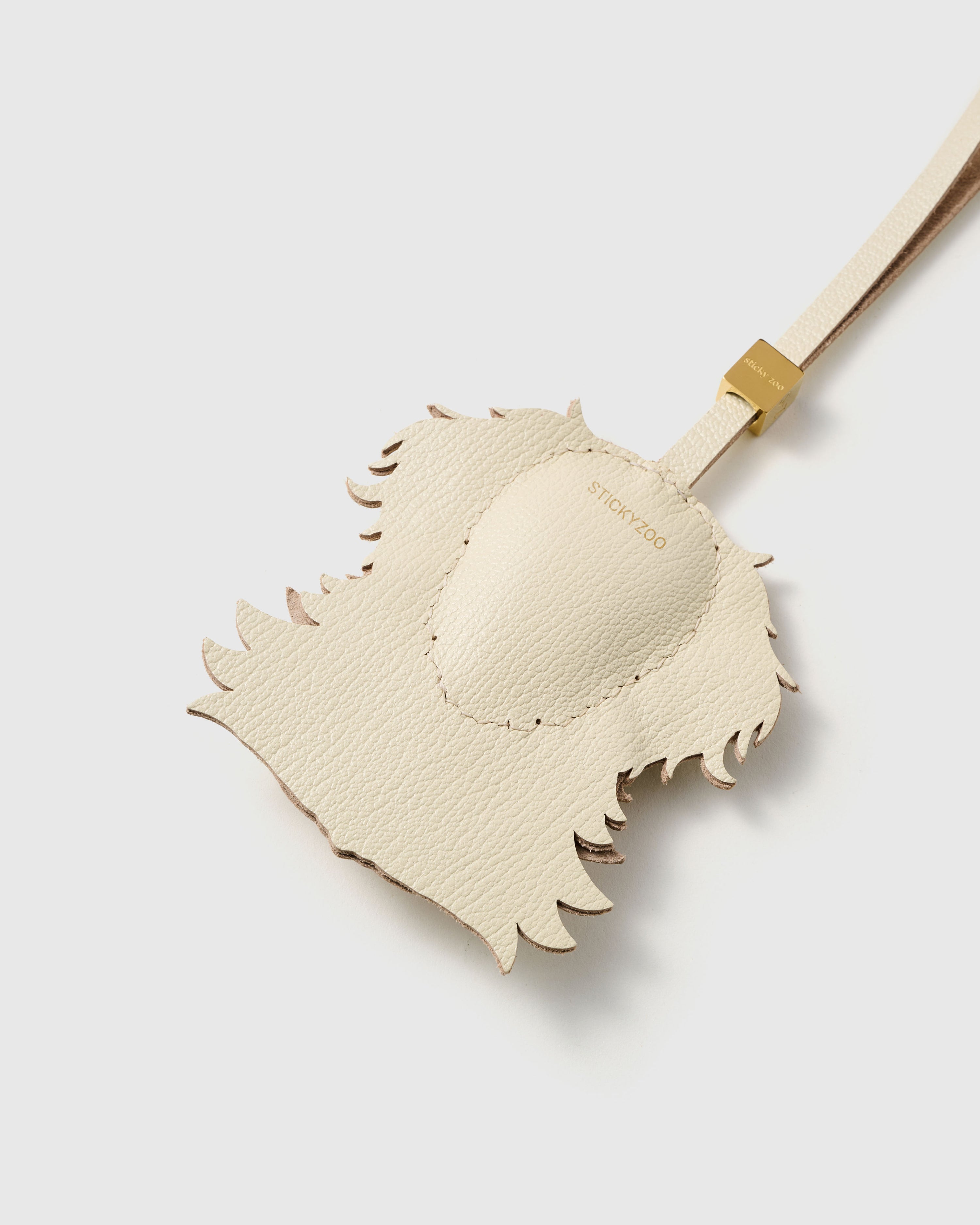 {{Finished on both sides.}} Back of the Golden Retriever charm — smooth cream French Alran goatskin with gold STICKYZOO debossing. Clean finish.
