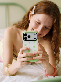 Hand holding the Lucky Star phone case while reading, fingers resting over the retractable MagSafe grip on the back.