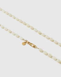 Macro close-up of the polished ivory resin beads and gold-plated clasp, each strap assembled by hand