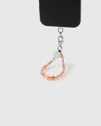 Peach crystal phone strap hanging from black phone case showing wrist carry functionality