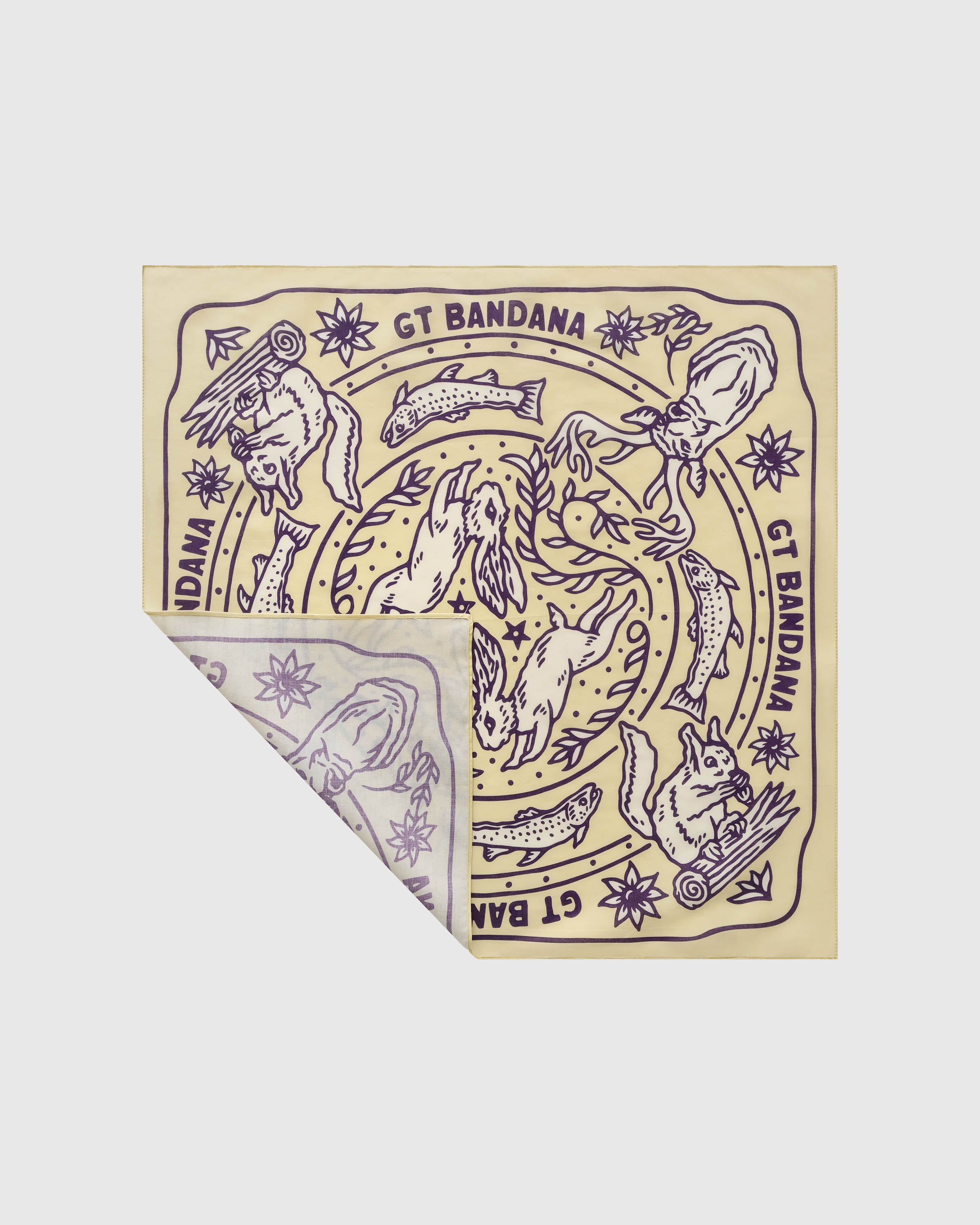 Butter-yellow silk scarf with a folded corner showing the aubergine woodland print and brand cartouche