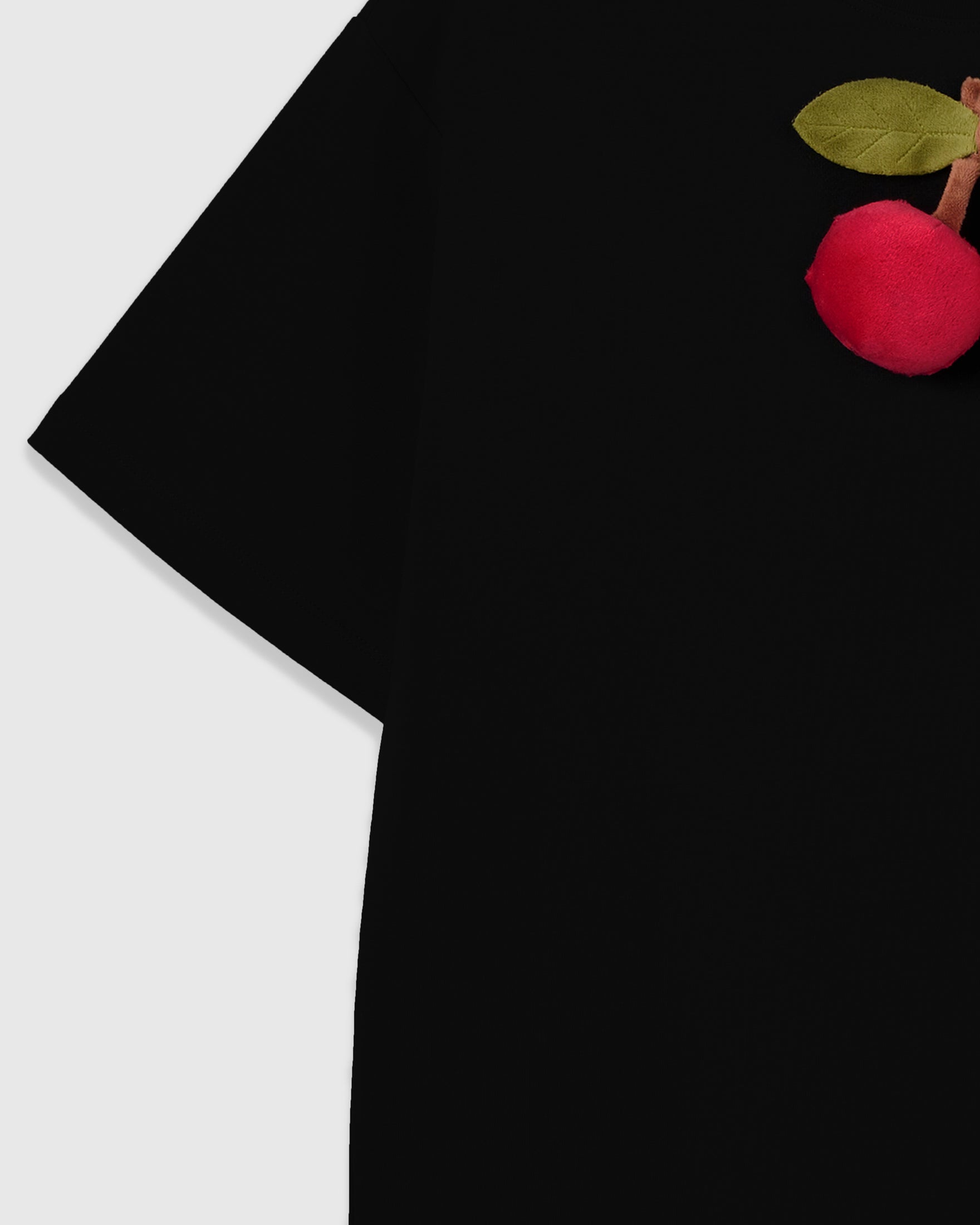 Detail of plush cherry appliqué edge on STICKYZOO Cherry T-Shirt in black with drop shoulder seam visible