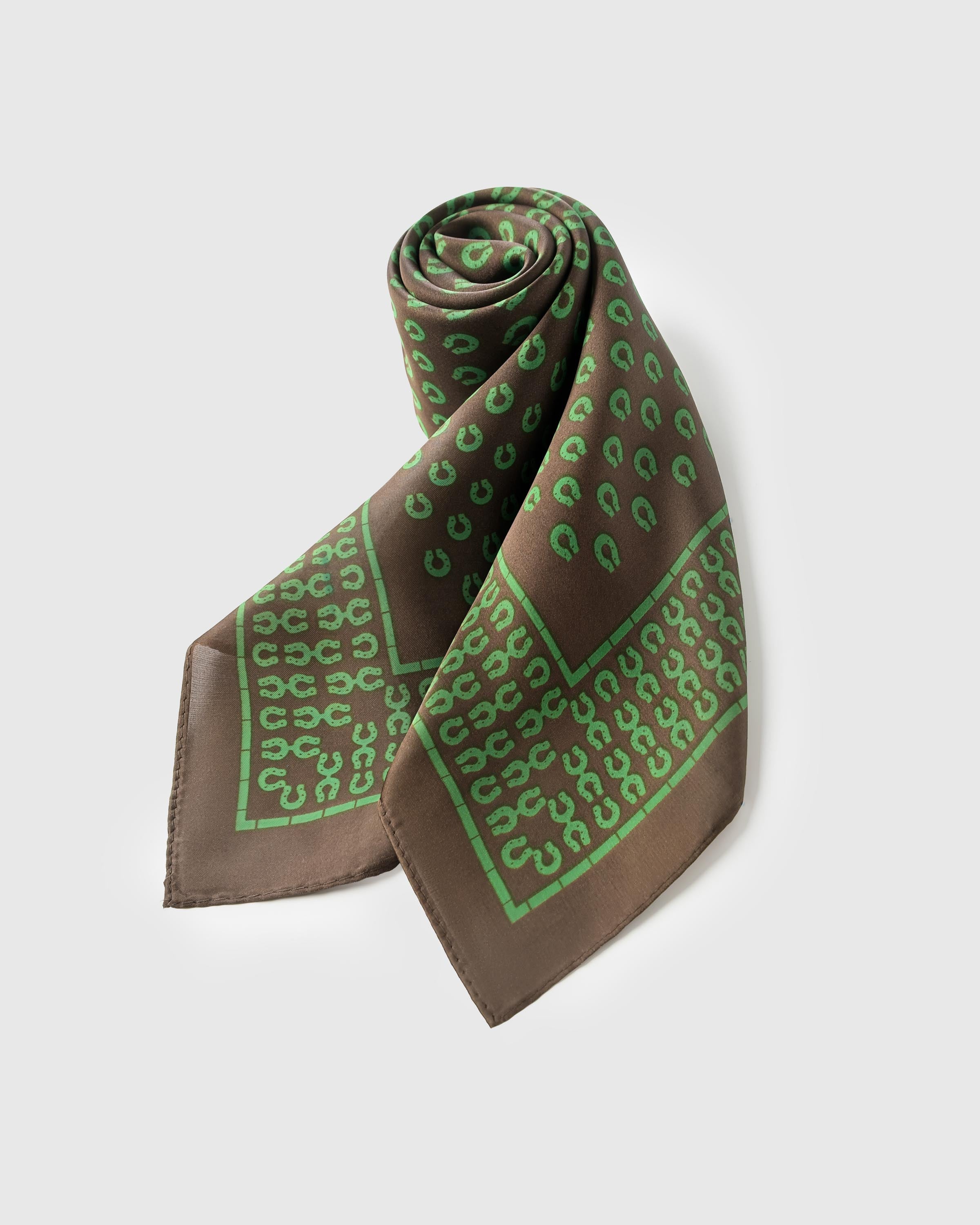Folded silk scarf rolled along the diagonal showing the chocolate field meeting the green stirrup border
```