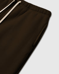Detail of elastic waistband with cream drawstring on brown premium cotton sweatpants showing fabric weight and construction