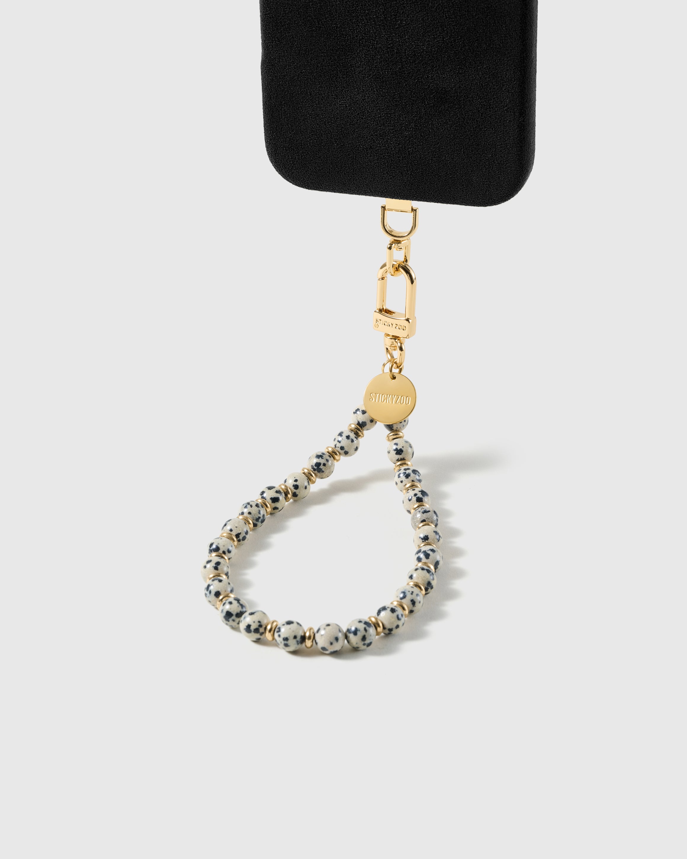 Cream speckled stone bead wrist strap clipped to a black phone case for hands-free carry