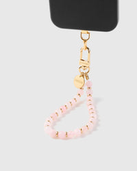 Soft pink stone phone strap hanging from black phone case showing wrist carry functionality