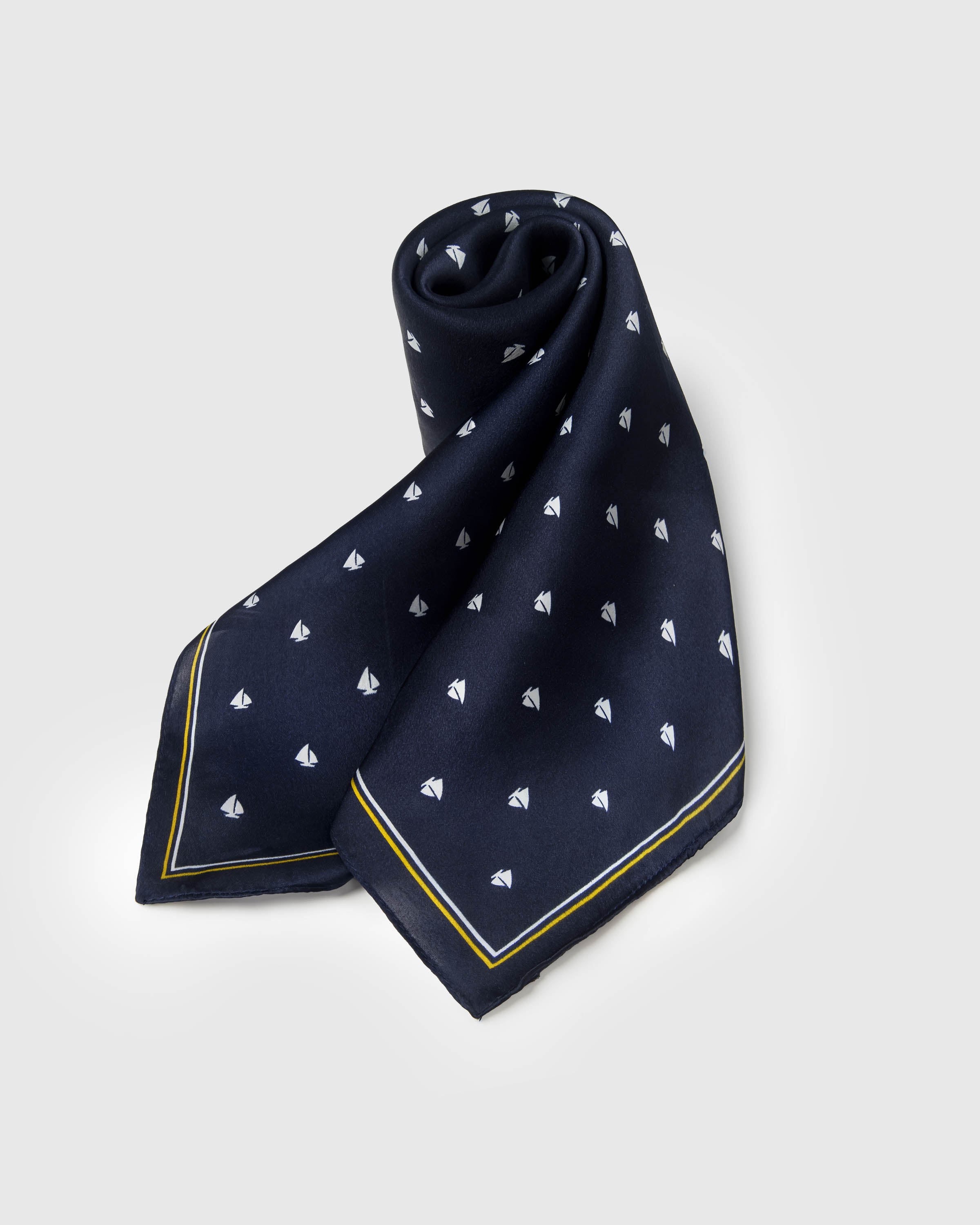 Silk regatta scarf coiled to show the deep navy drape and the soft hand of pure silk
```