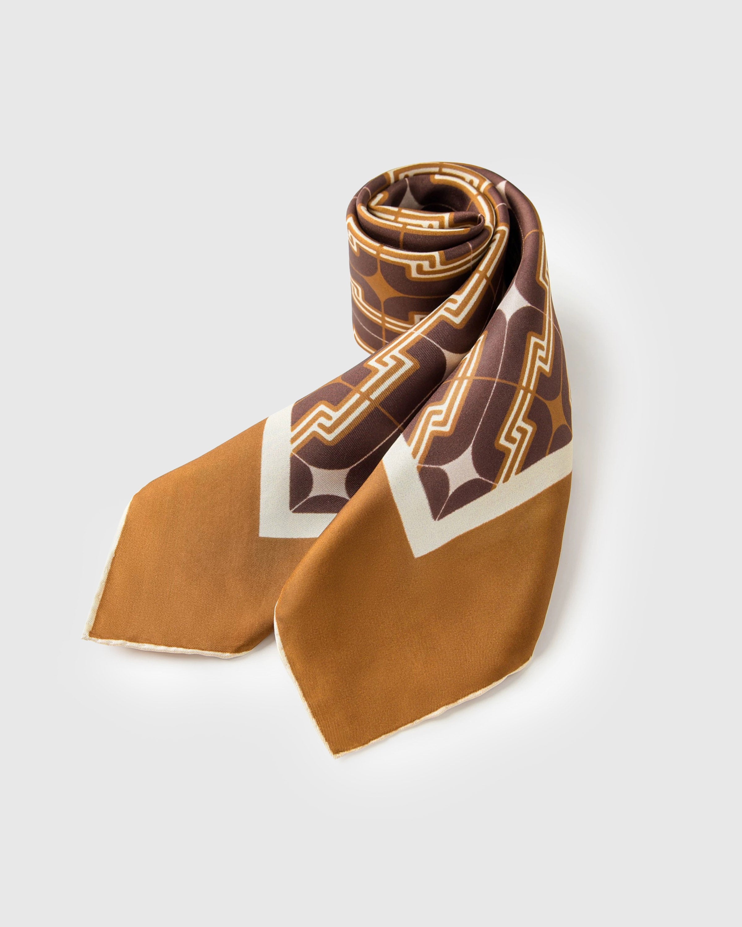 Tobacco silk scarf rolled into a soft loop showing the deco chain pattern and warm border
```
