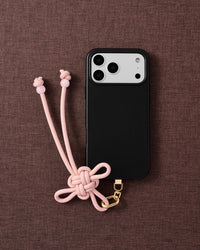 Rose knot phone strap on fabric background showing full knot detail and bead-tipped tails