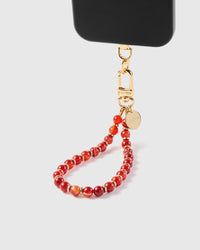 Scarlet stone phone strap hanging from black phone case showing wrist carry with gold spacer beads