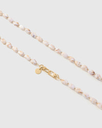 Close-up of elongated blush and cream marble-style beads with gold spacers and engraved STICKYZOO hardware