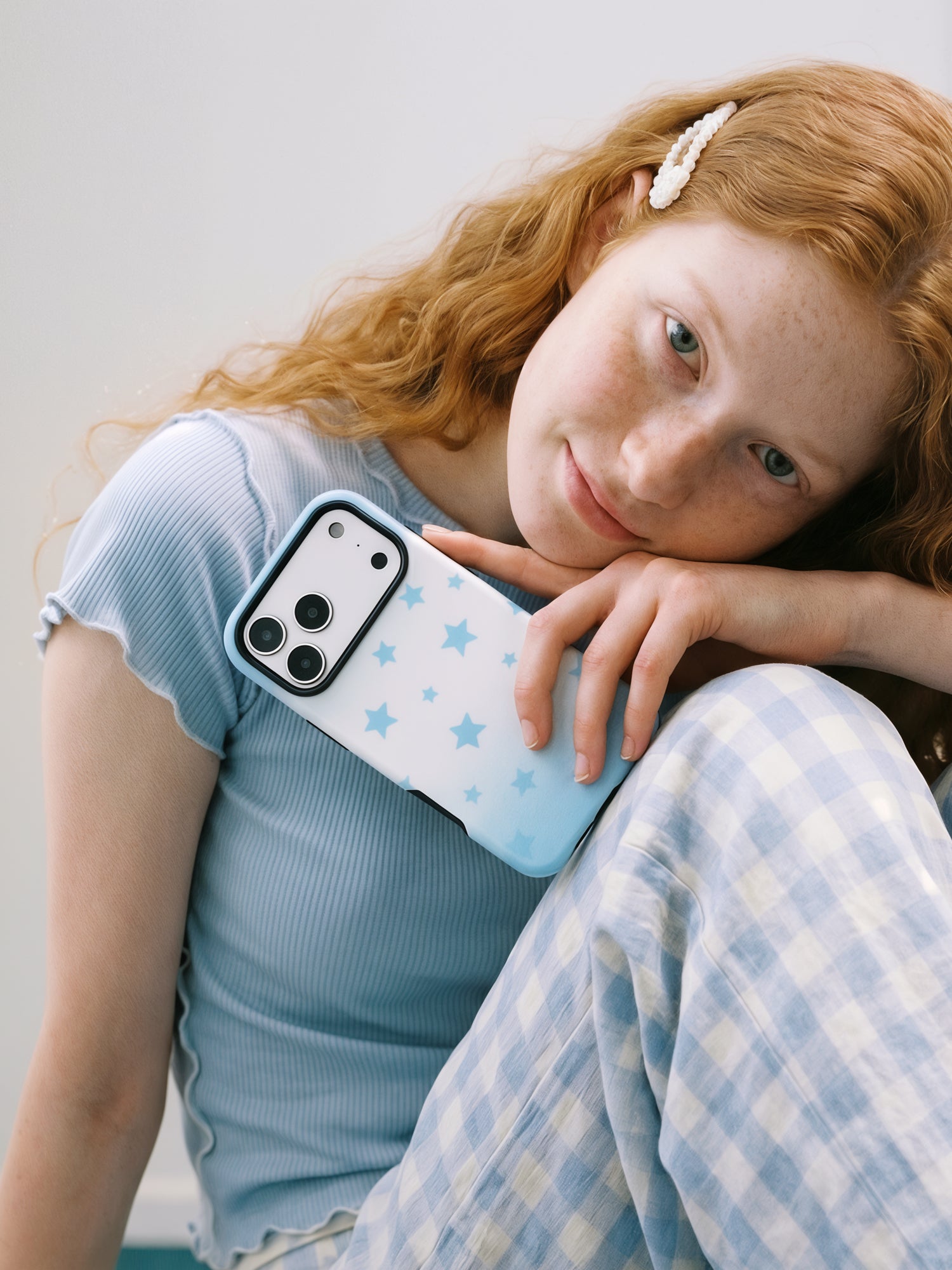 Sky Starfall phone case held close, the scattered blue stars on the white-to-blue case facing out
