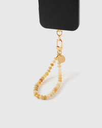 Saffron agate orbit phone strap hanging from black phone case showing warm golden stone beads