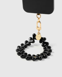 Noir heart phone strap hanging from black phone case with gold hardware showing wrist carry