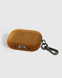 Back view of warm camel Alcantara case showing USB-C port, speaker cutouts, and metal carabiner