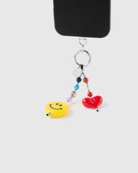 Smiley heart charm phone strap hanging from black phone case showing dual-strand design