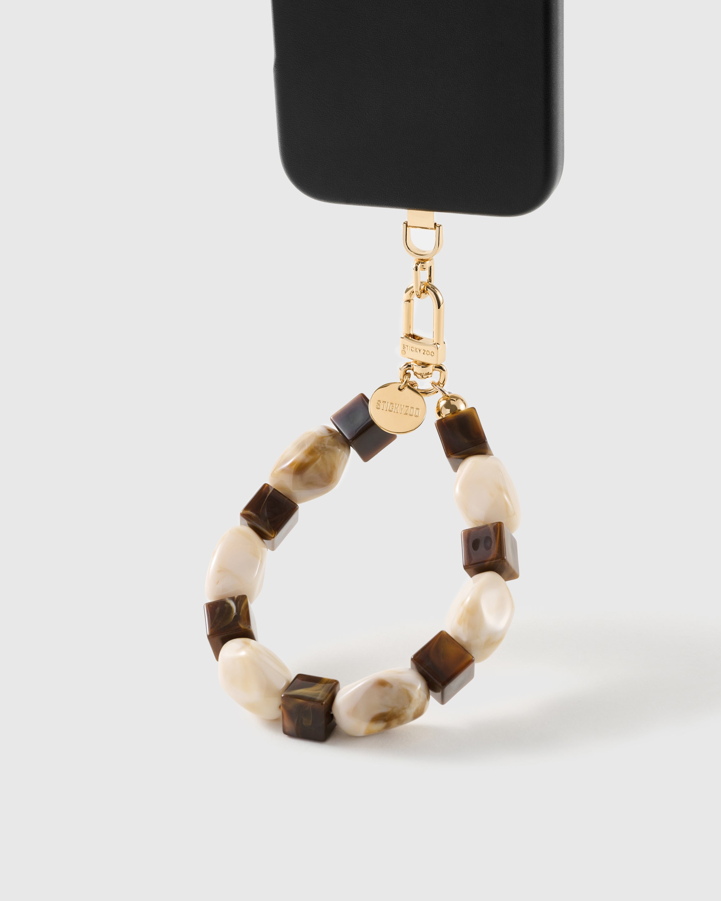 Cocoa marbled bead wrist strap clipped to a black phone case for hands-free carry