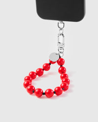Scarlet sphere phone strap hanging from black phone case showing wrist carry functionality