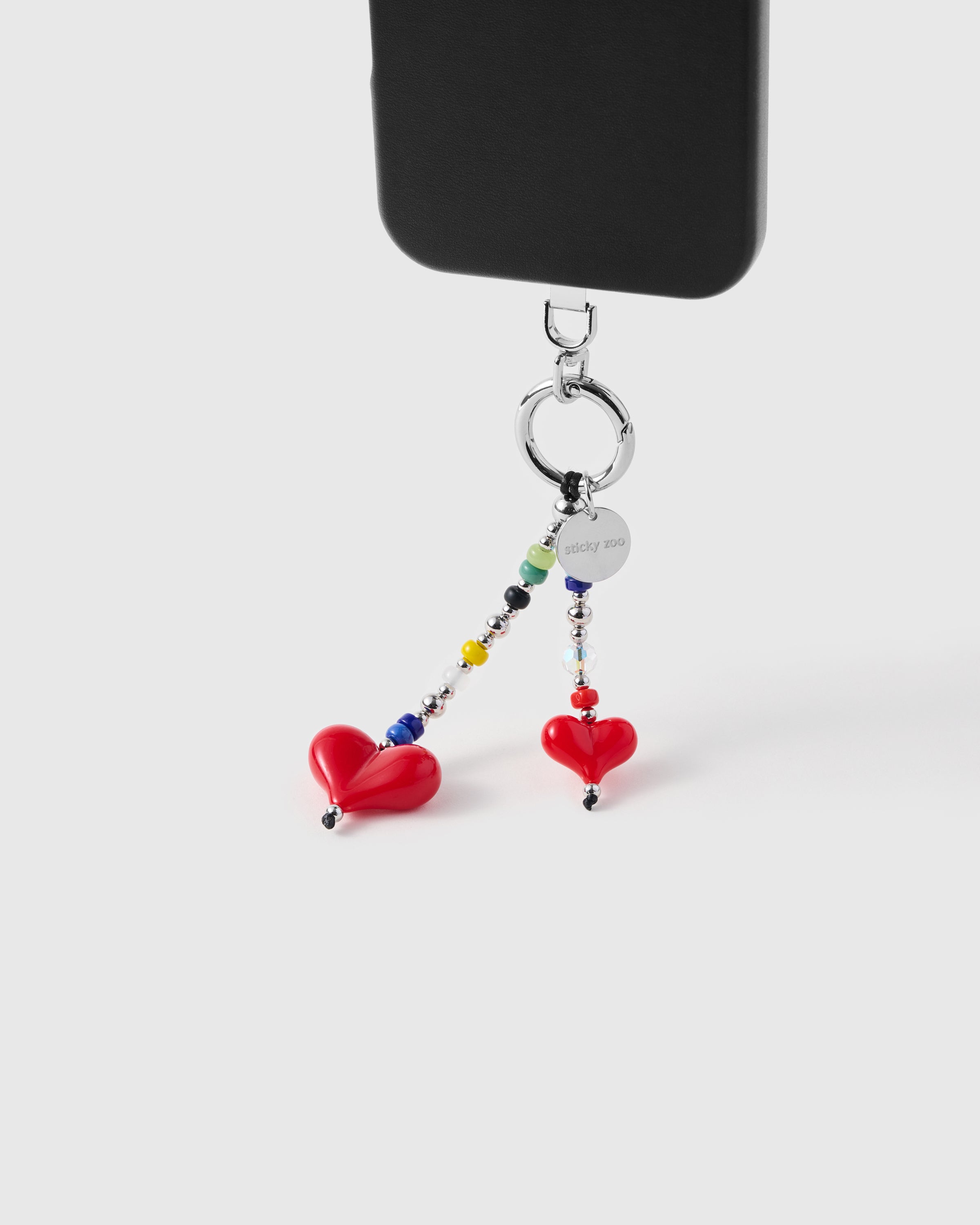Double heart dangle strap hanging from black phone case showing daily carry
