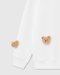 Detail of multiple plush bear faces on white cotton showing embroidered eyes and dimensional fur texture