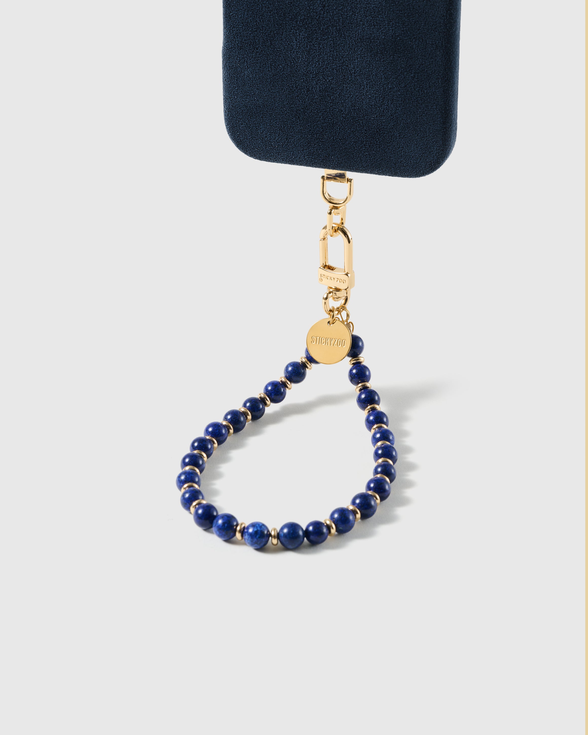 Cobalt-blue stone bead wrist strap clipped to a black phone case for hands-free carry