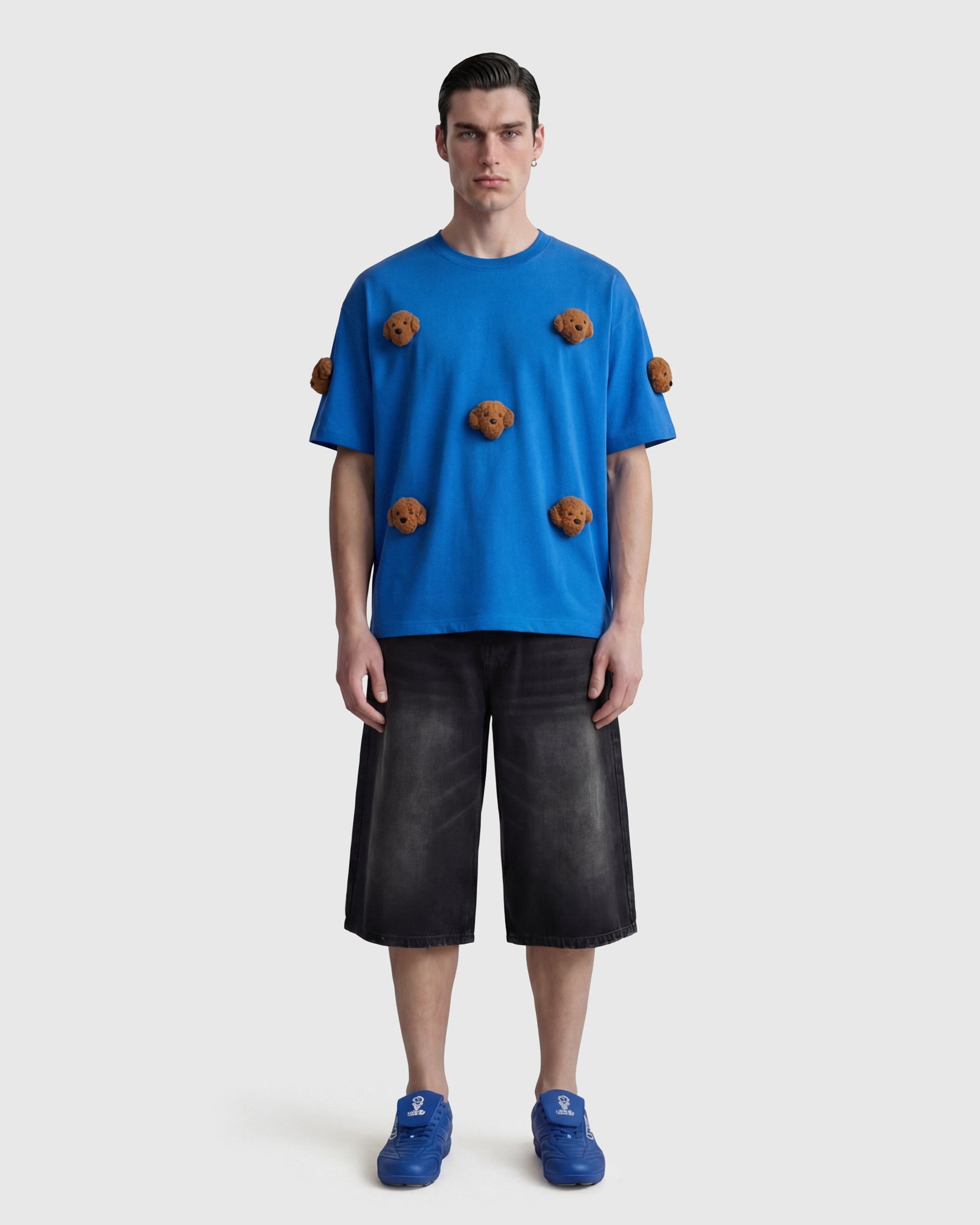 Model wearing STICKYZOO Poodle Parade T-Shirt in blue showing dropped shoulders and plush poodles
