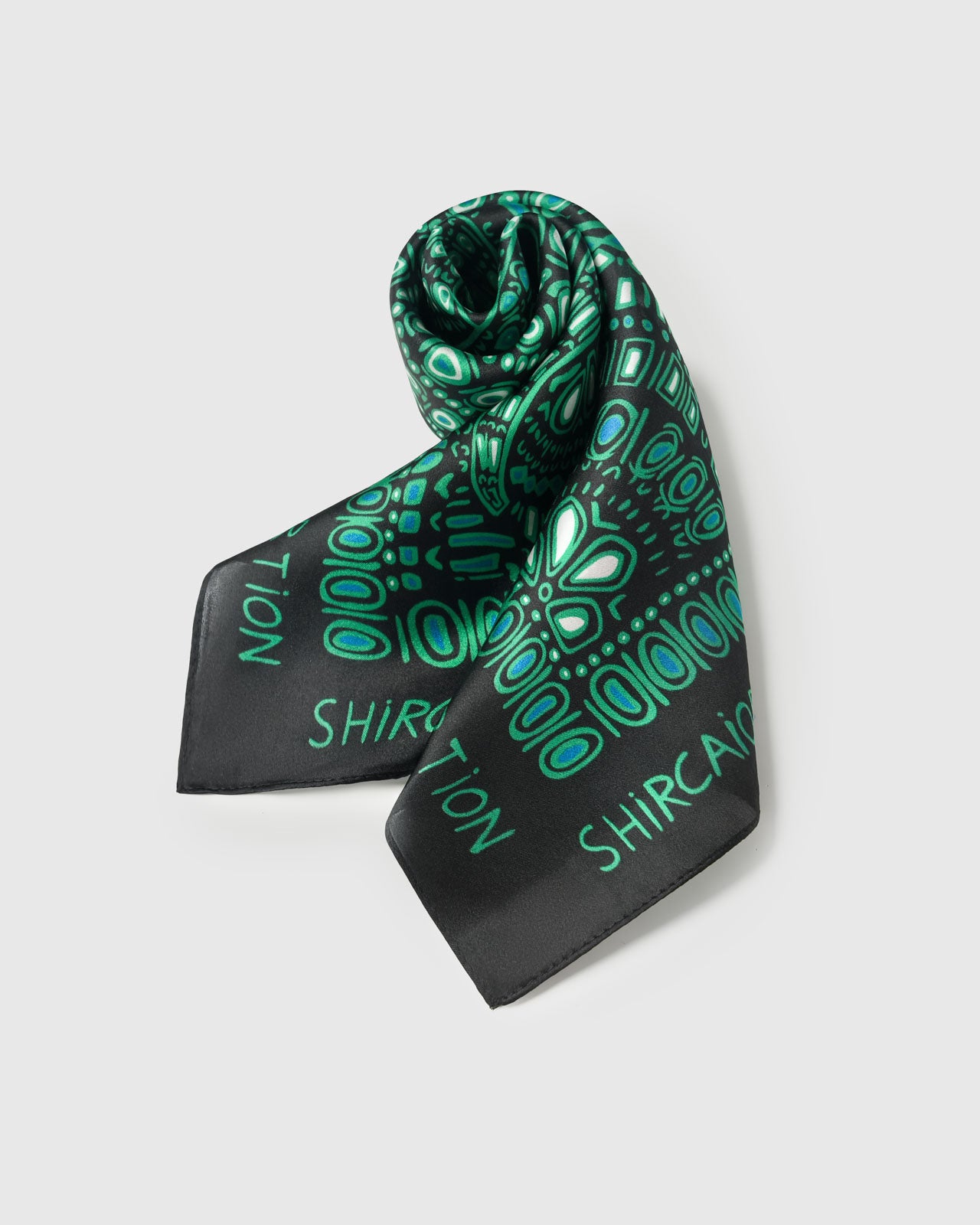 Silk scarf draped to show the emerald dotwork print fanning across the silk and the black border catching light
```