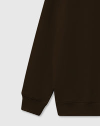 Detail of rolled plush croissant near hem on brown base showing hand-stitched dimensional construction