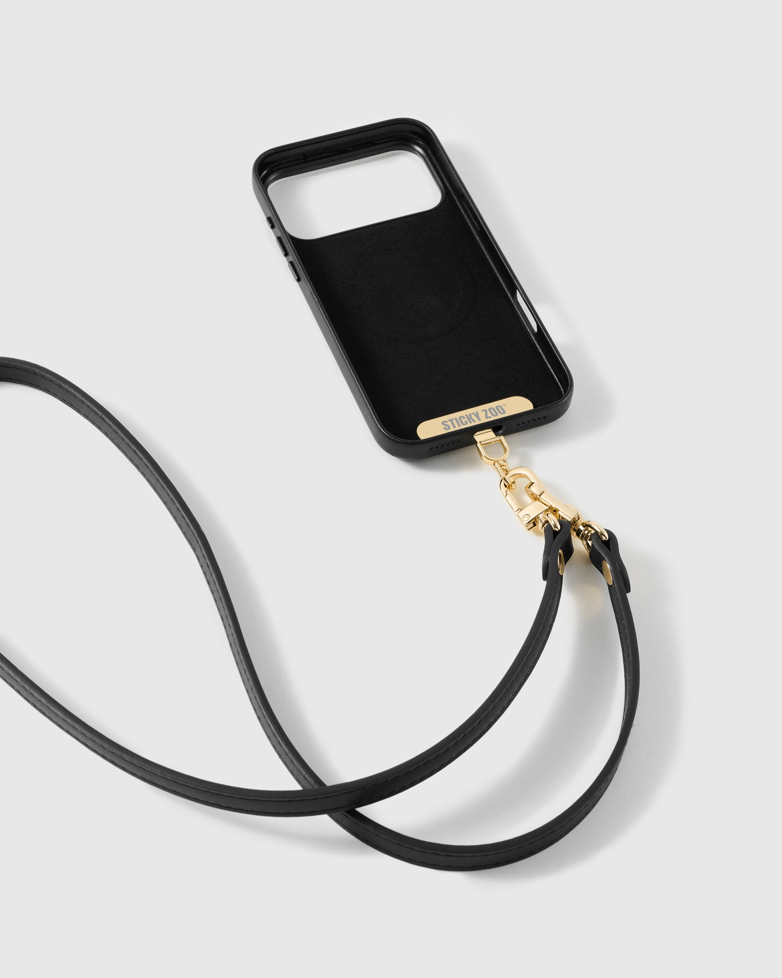 STICKYZOO black vegan-leather phone strap attached to a black phone case with a charging-port opening using the included Phone Strap Card; case sold separately
