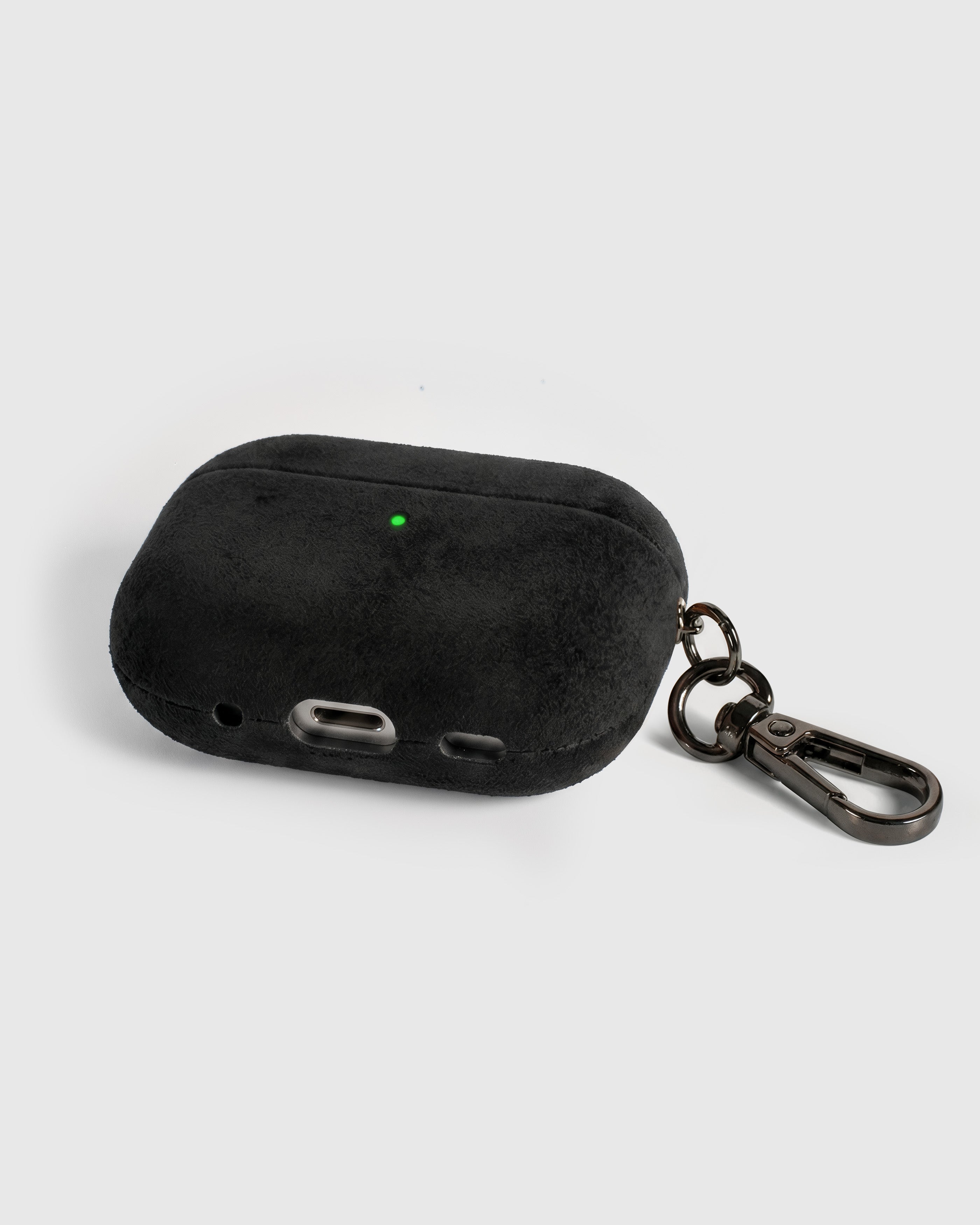 Back view of black Alcantara case showing USB-C port, speaker cutouts, and metal carabiner