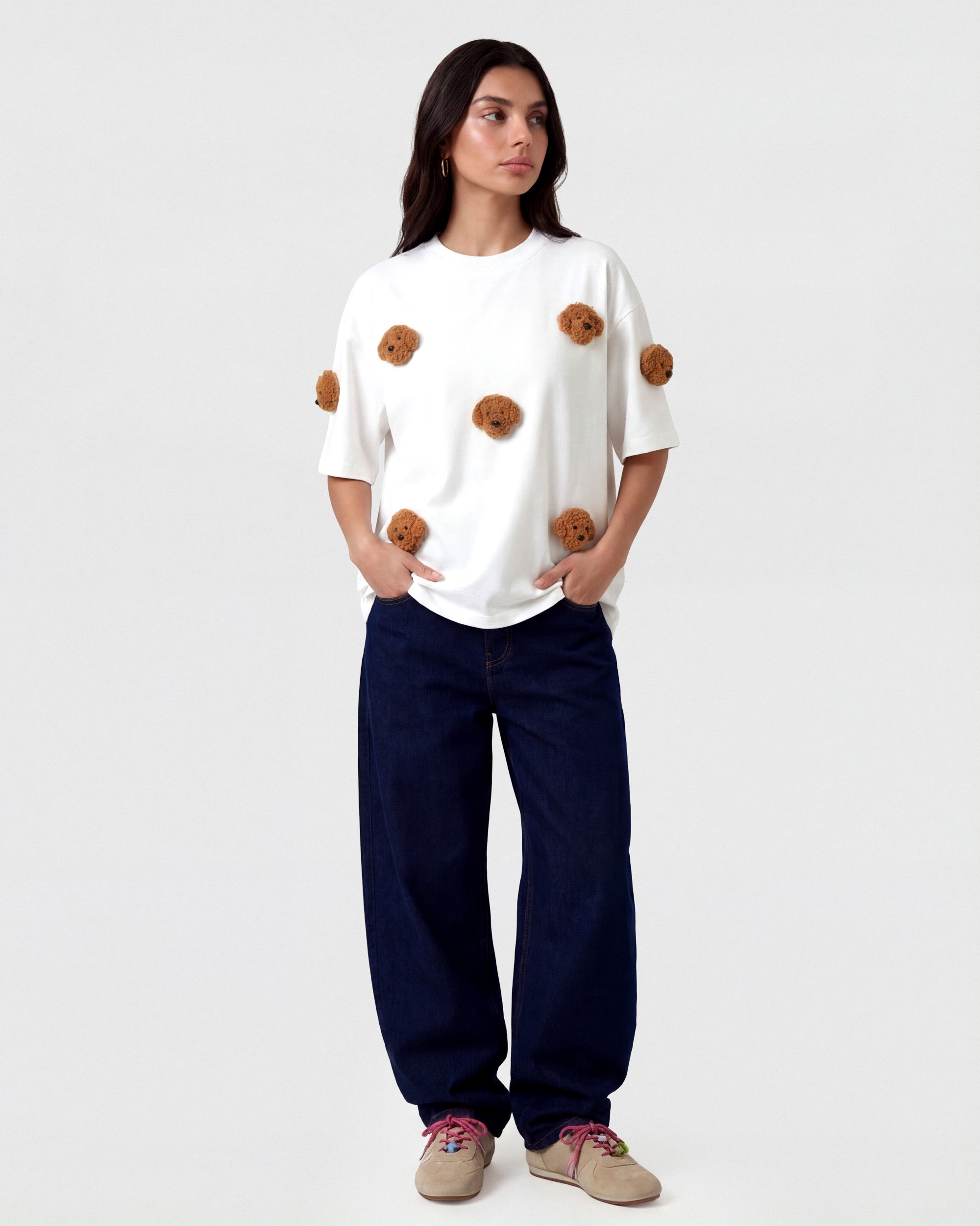 {{Not printed — stitched}} Model in white Poodle Parade T-Shirt with hands in pockets showing relaxed silhouette