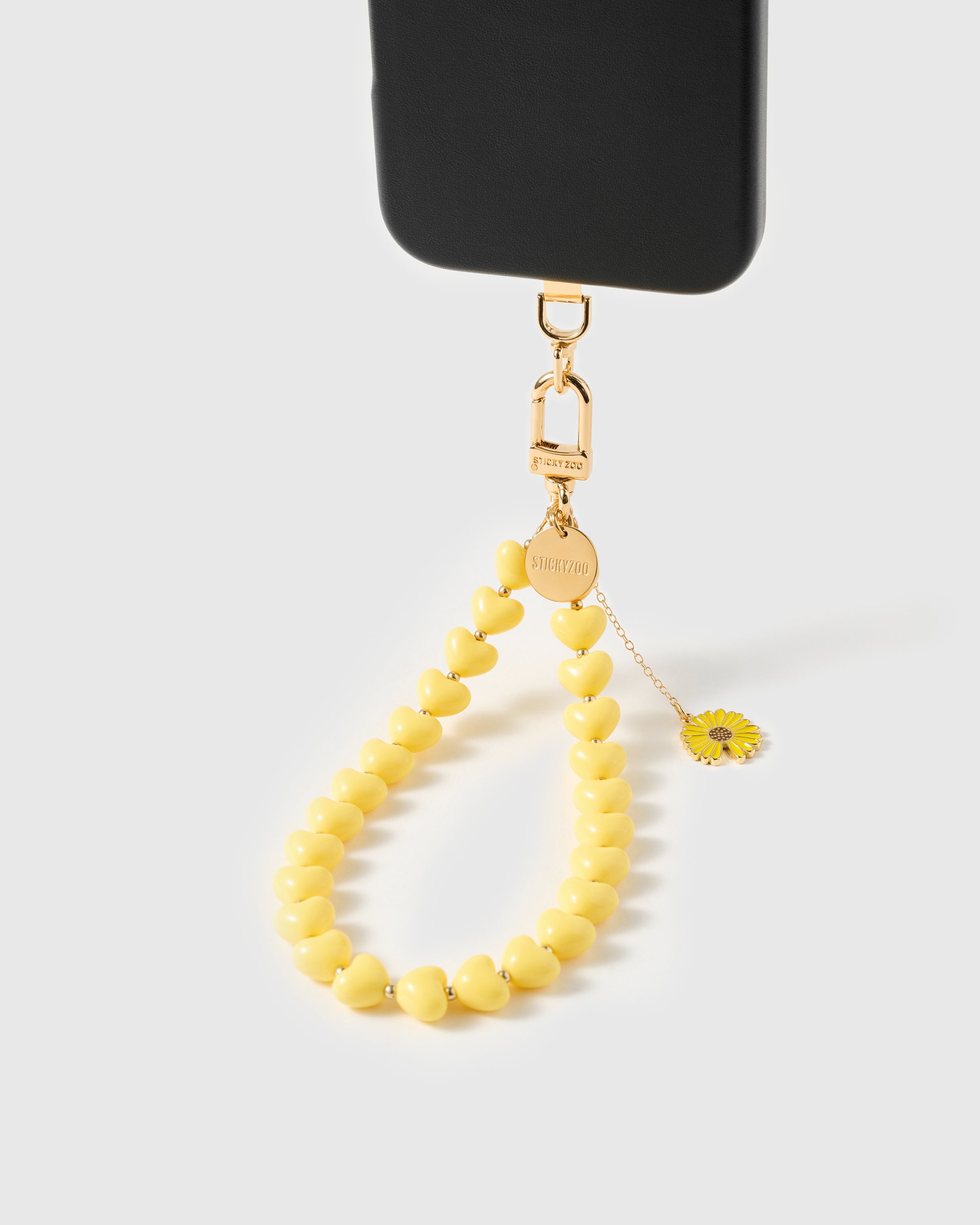 Gold daisy charm on fine drop chain swinging against glossy lemon resin heart beads — Loved by Thousands