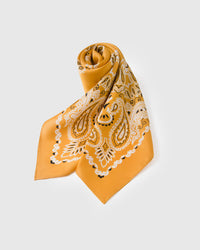 Rolled saffron silk scarf knotted to show the paisley motif and the small-square bandana format
```